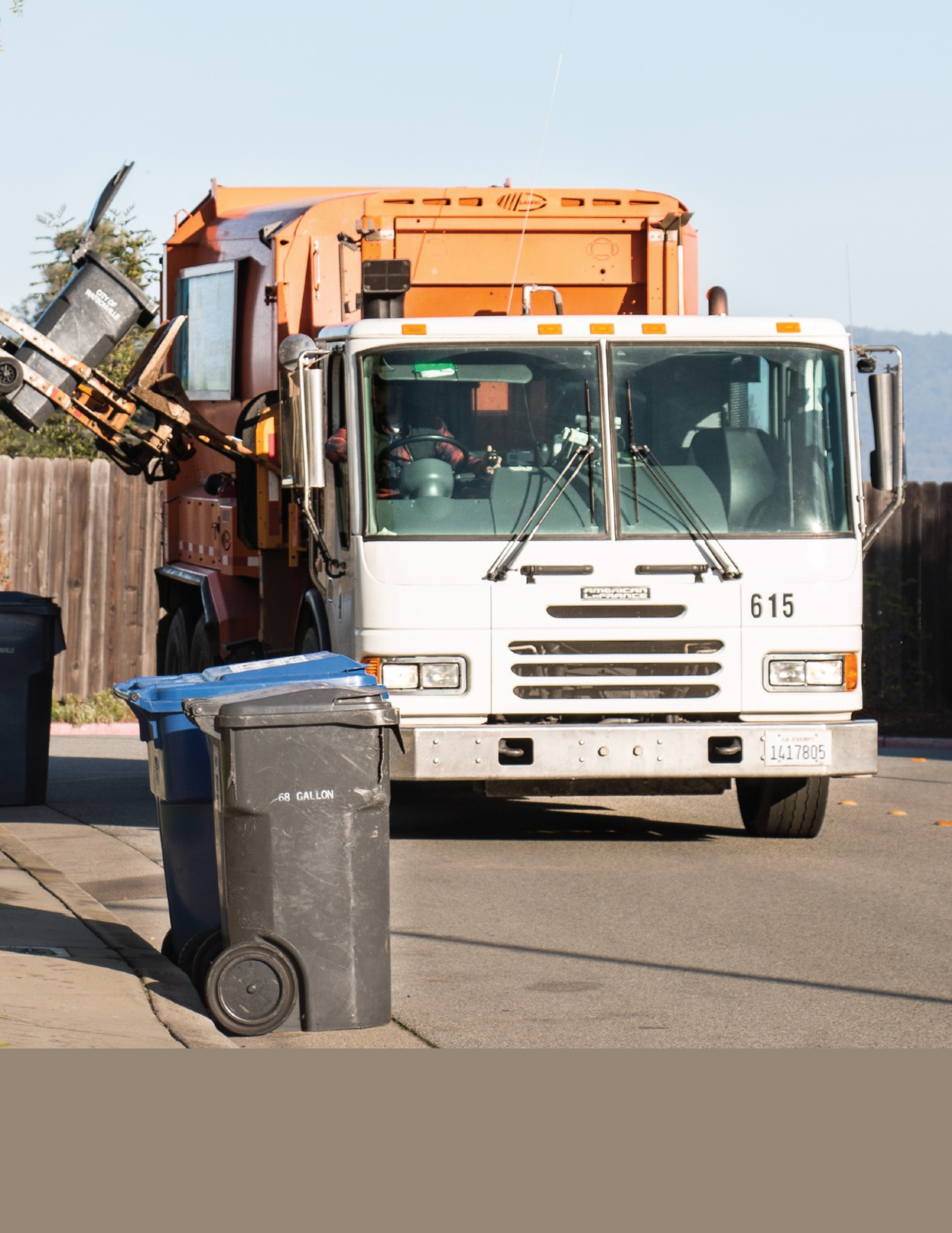 A photo of a garbage truck picking up trash bins on a street 