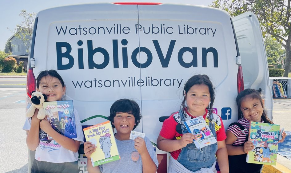 photograph of children standing next to the library bibliovan holding up books