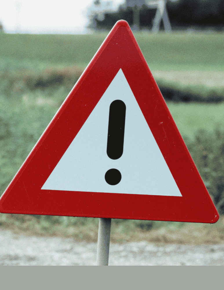 Hazard sign in an open green field 