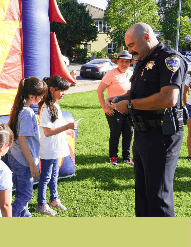 Police captain giving two young children a police sticker 