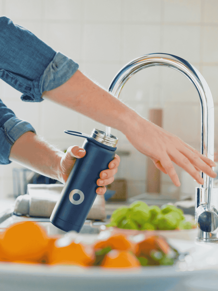 Photo of a person filling reusable water bottle with water from their kitchen tap