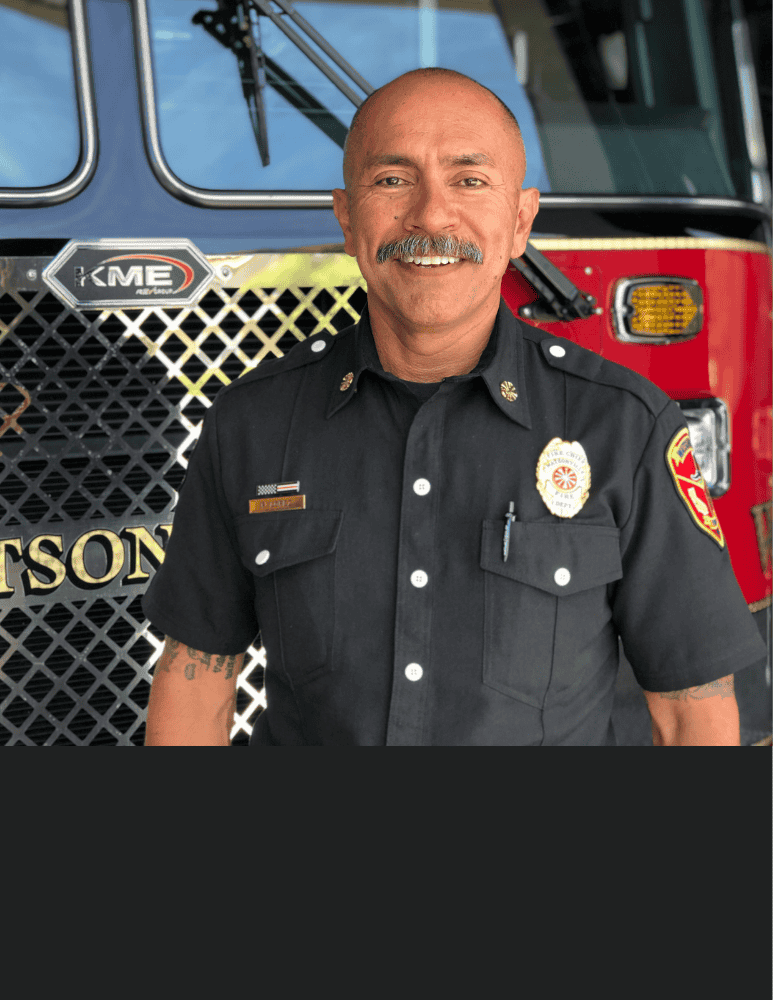 A headshot of Chief Lopez standing in front of a fire truck 