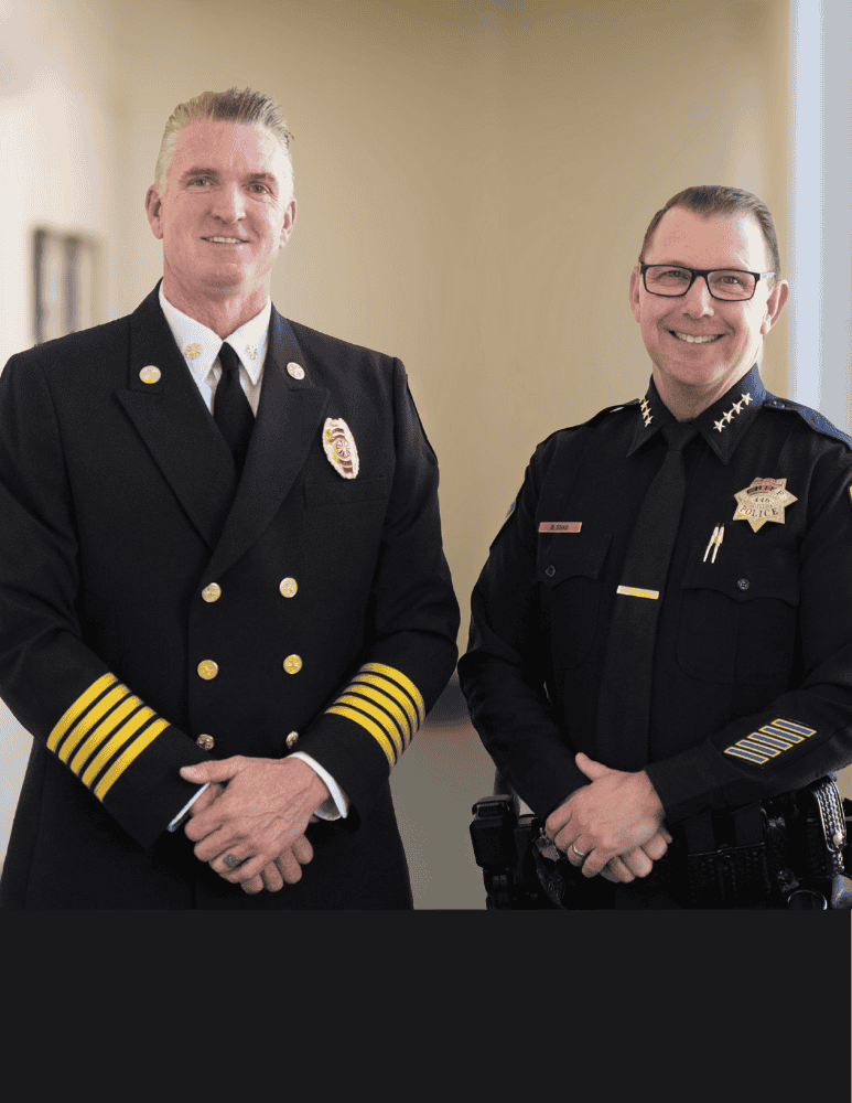 Fire Chief Corey Schaefer and Police Chief Brian Shab stand side by side indoors.