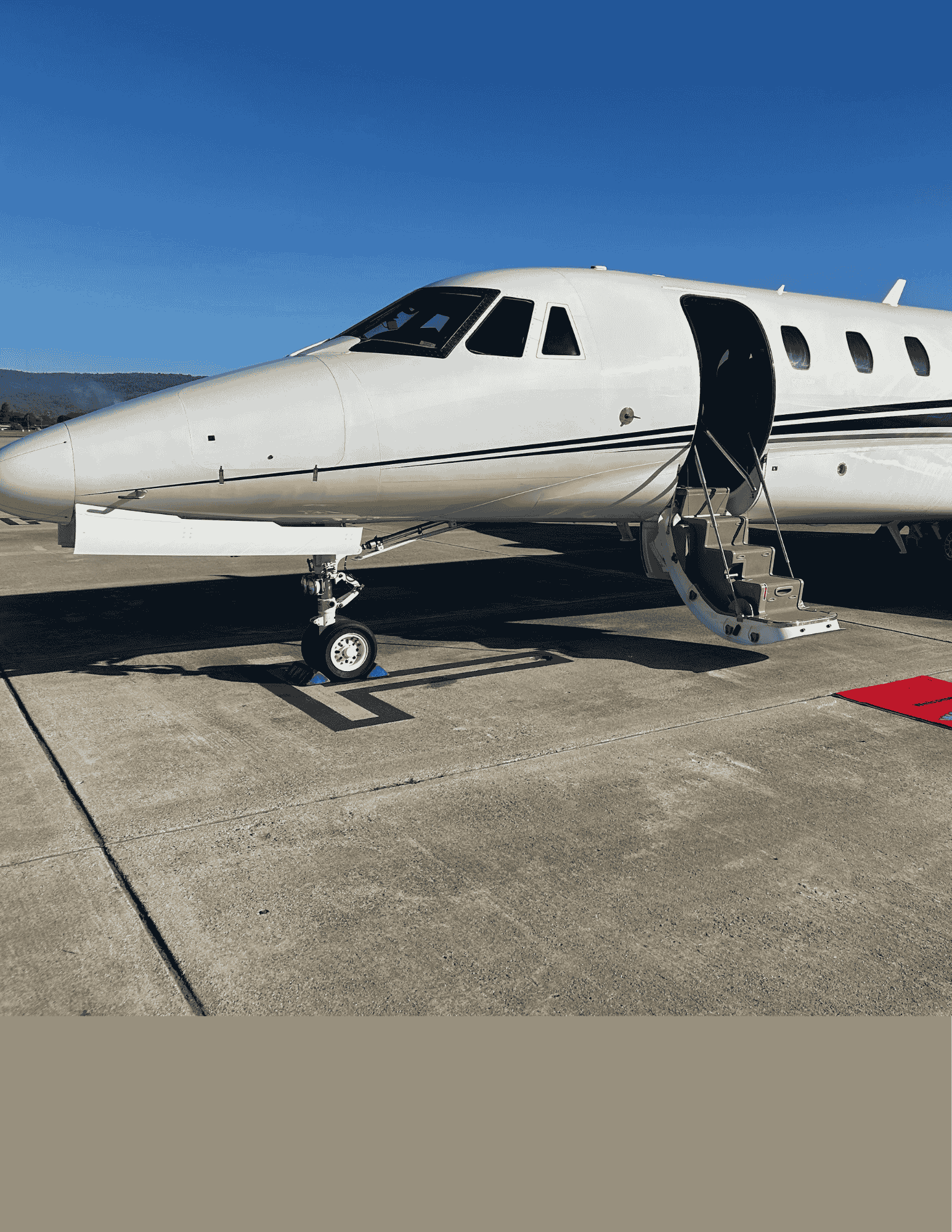 Private jet parked on an airport tarmac with its door open and stairs lowered