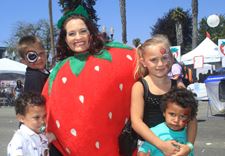 A woman in a strawberry costume with kids.