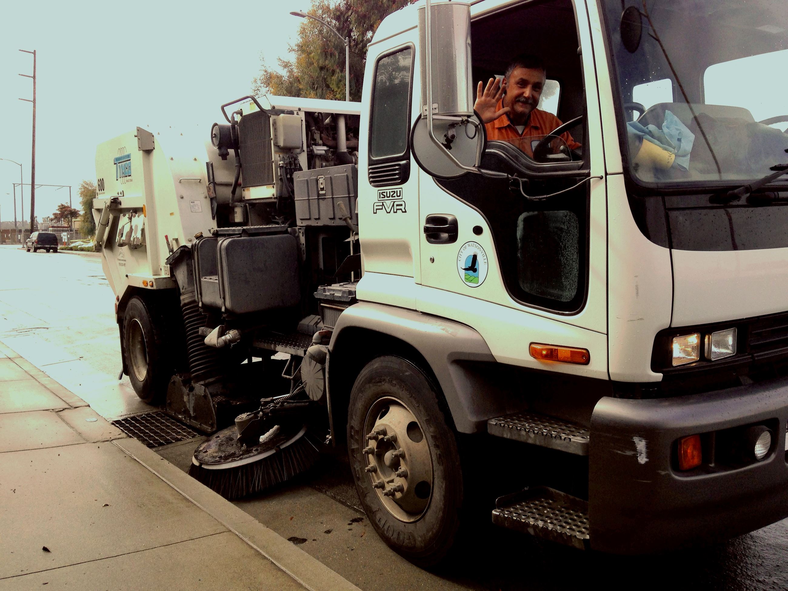 Street sweeper driver waving from truck
