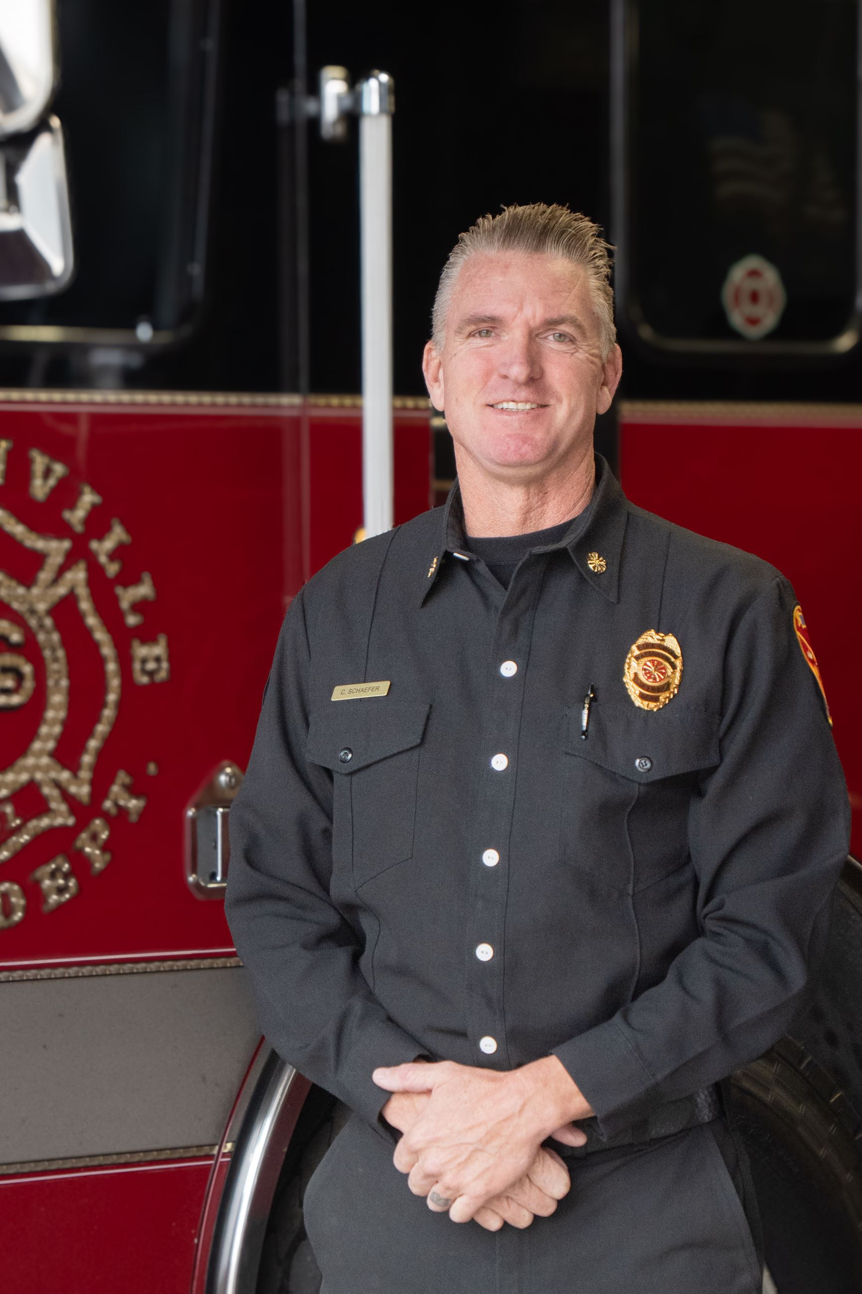Newly appointed Fire Chief Schaefer standing in front of a firetruck for his headshot