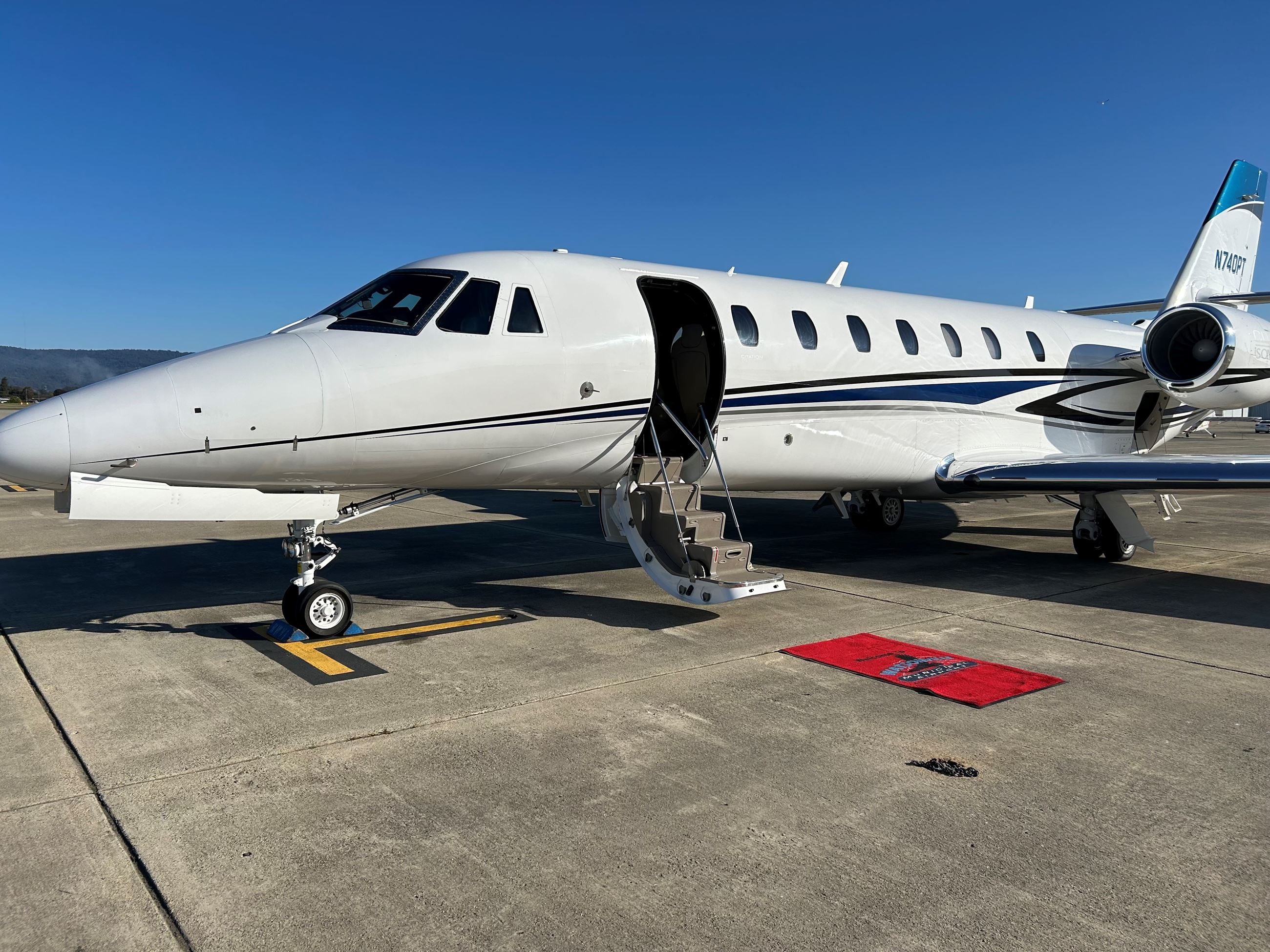 Private jet parked on an airport tarmac with its door open and stairs lowered, 