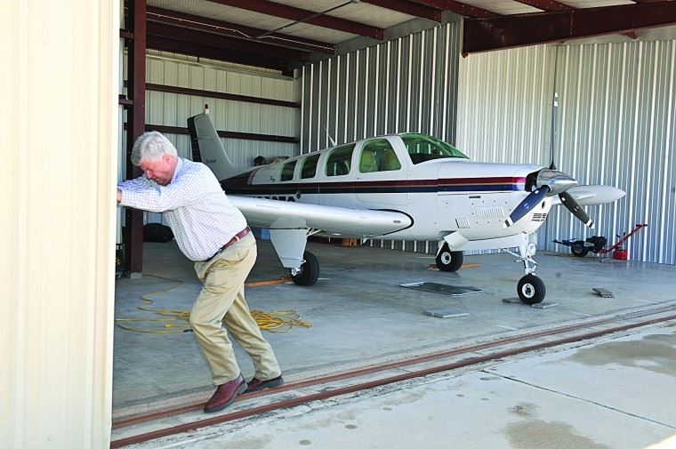 Man Opening Hangar Door with Airplane in Hangar